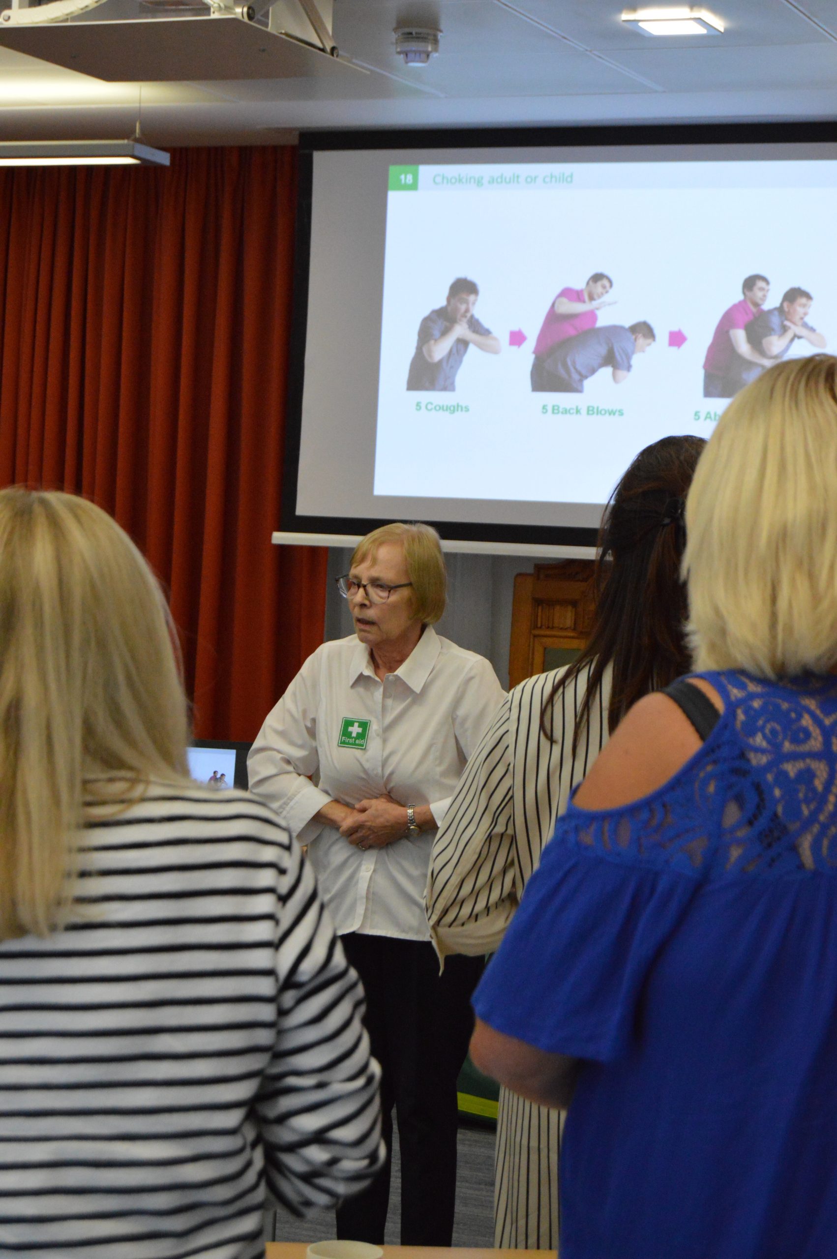 Lady demonstrating Abdominal thrusts in EFAW Emergency First aid at work