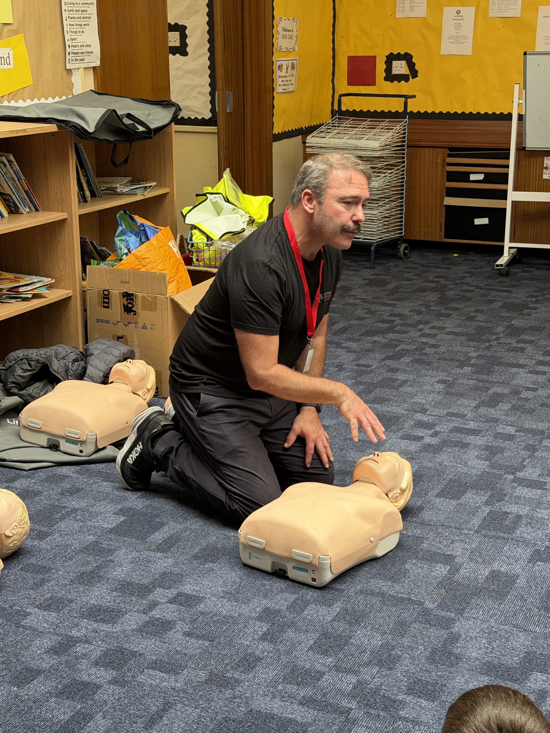 instructor showing children first aid training at school.