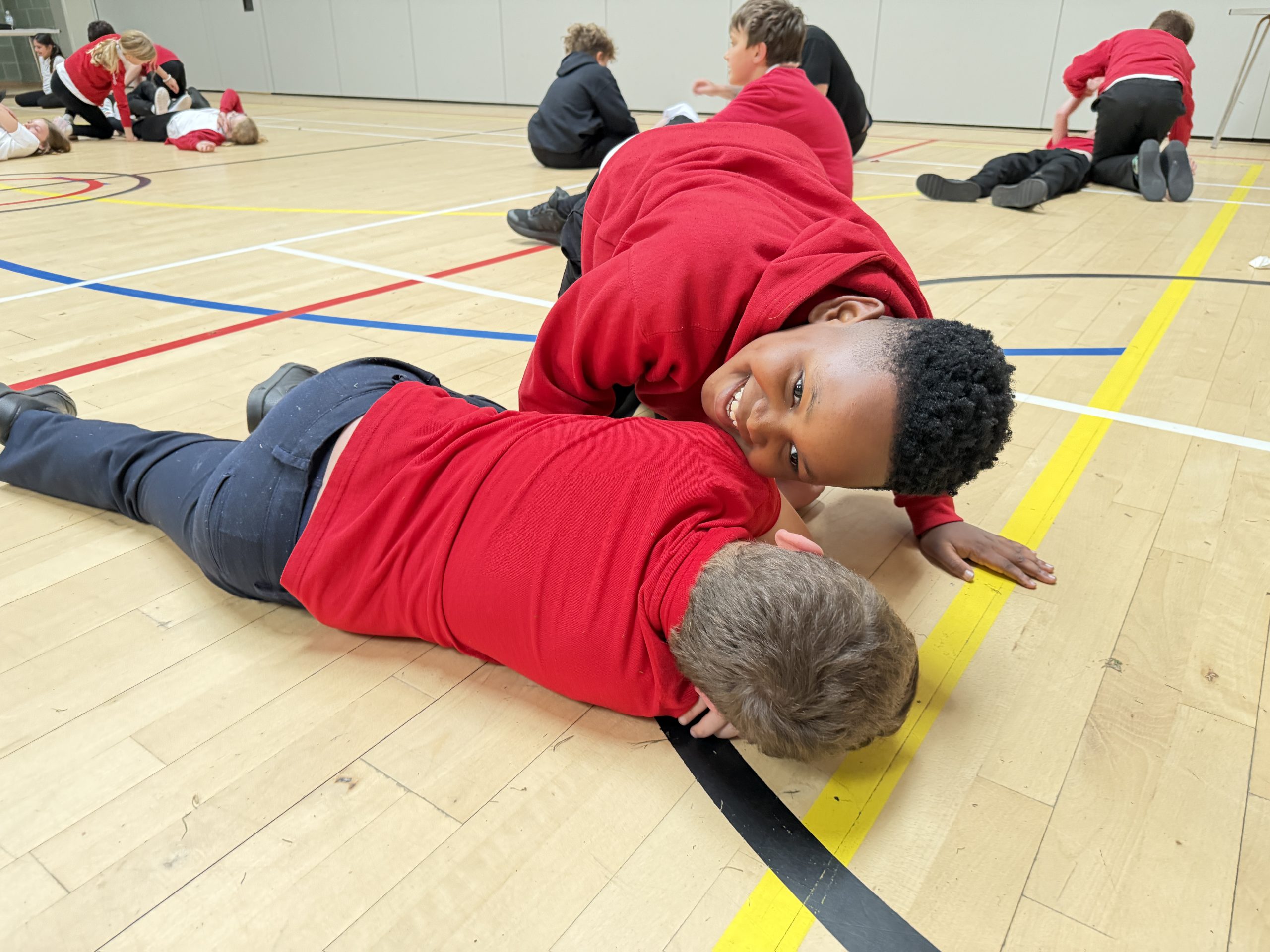 Boy putting student in recover position during Mini Medic first aid training course.